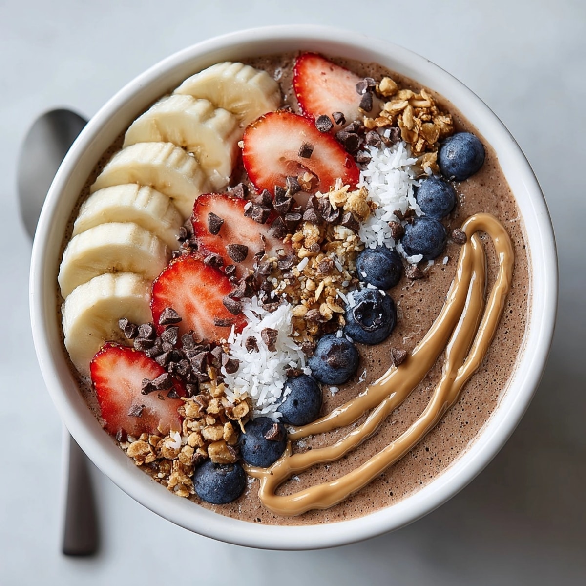 Breakfast chocolate peanut butter protein smoothie bowl featuring vibrant fruit and coconut flakes for a nourishing start.