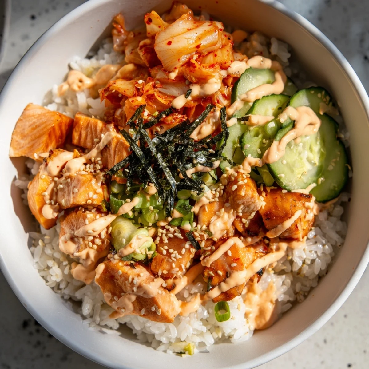 Savory crispy salmon rice bowl served with garlic, creamy mayo, and tangy kimchi.