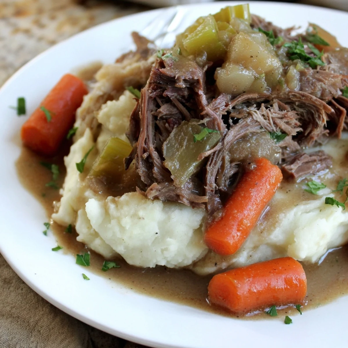 Tender slow cooker pot roast served with creamy mashed potatoes and fresh parsley.  