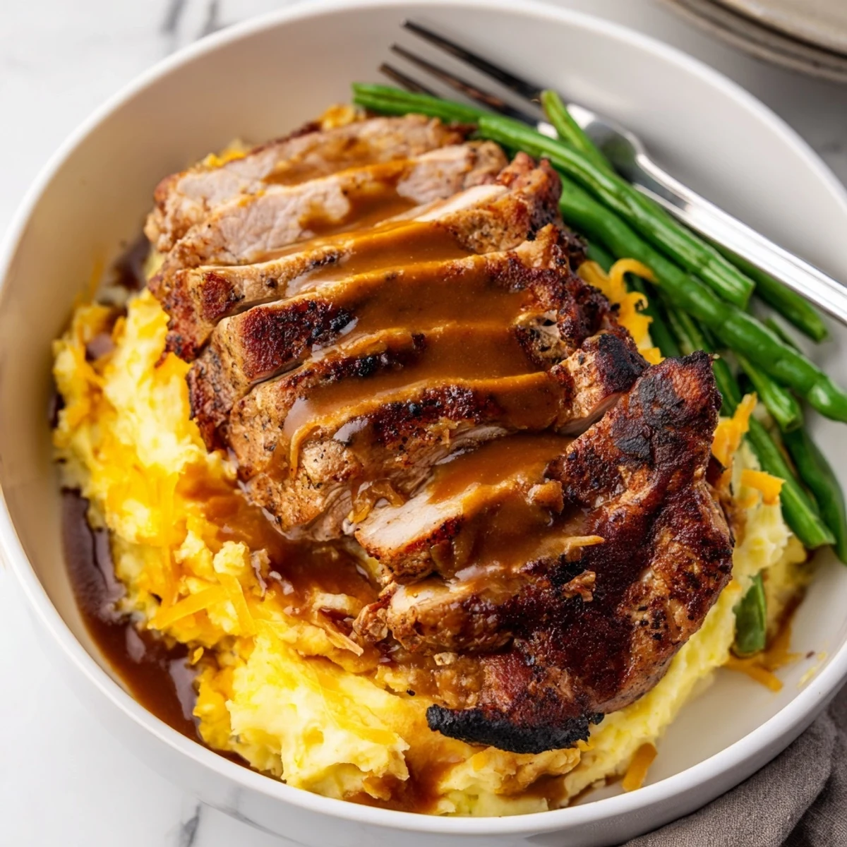 Comforting pork chops and cheddar mash bowl paired with vibrant green beans.  