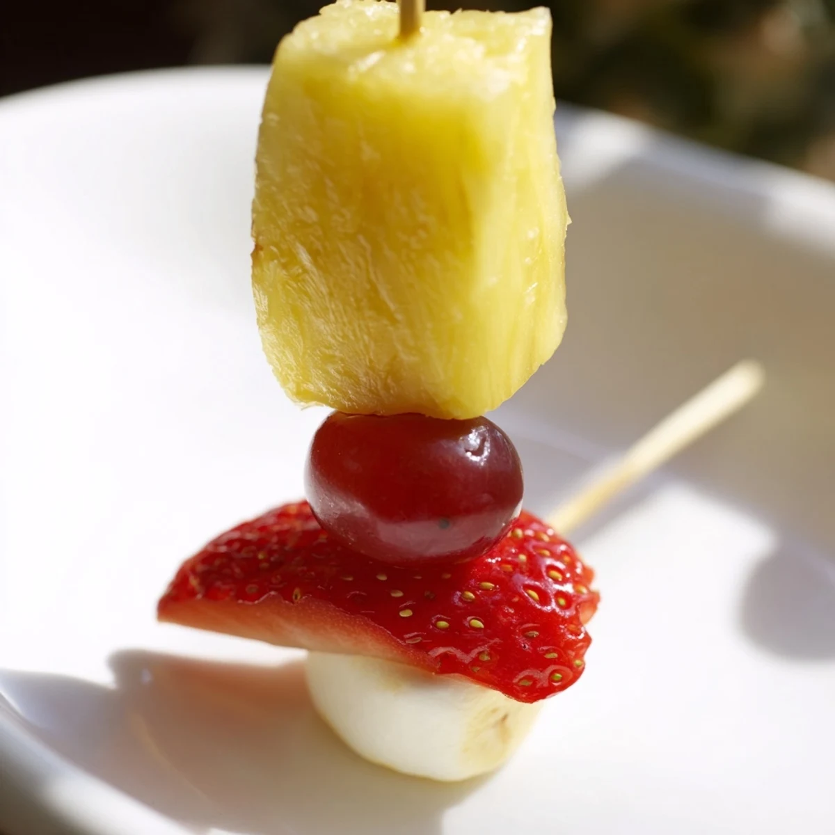 Festive Christmas Light Fruit Skewers bursting with colorful grapes, strawberries, and pineapple, ready to eat.