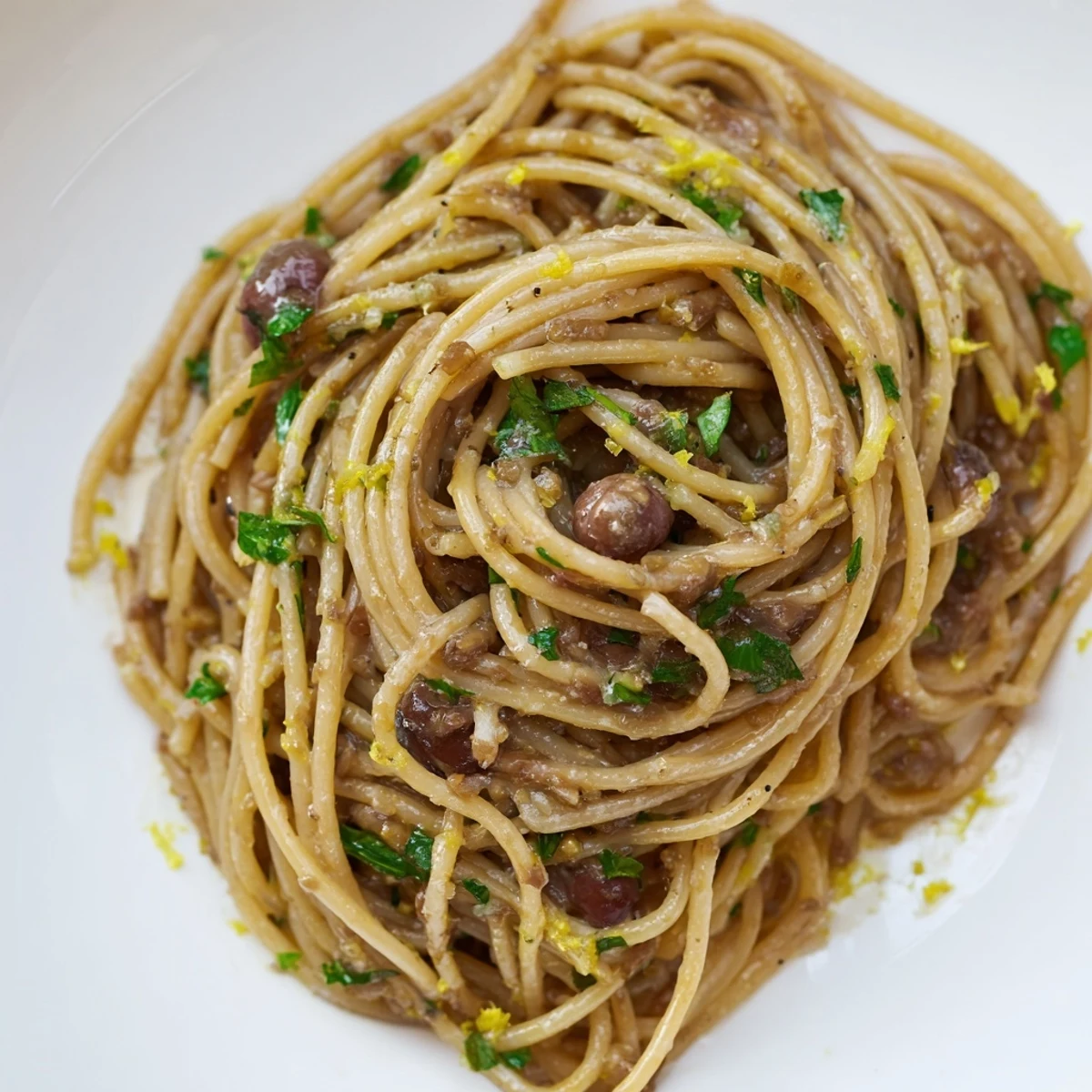 Steaming bowl of olive tapenade pasta, a bright Mediterranean meal, garnished beautifully with parsley.