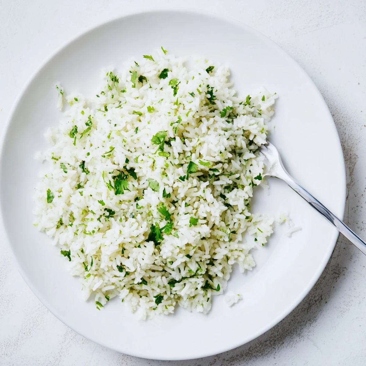 Steaming bowl of homemade Cilantro Lime Rice topped with chopped cilantro and lime wedges.