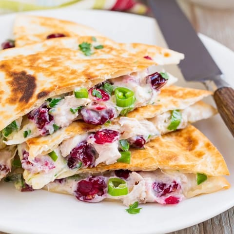 Vibrant cranberry jalapeño dip quesadillas served warm with fresh cilantro garnish.  