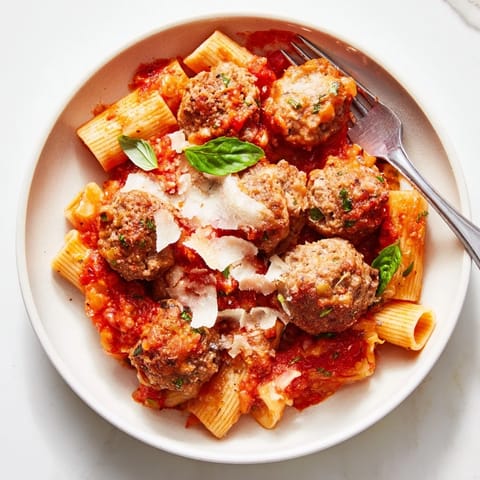 Hearty Italian Meatball Pasta Skillet topped with melted cheese and fresh basil.   