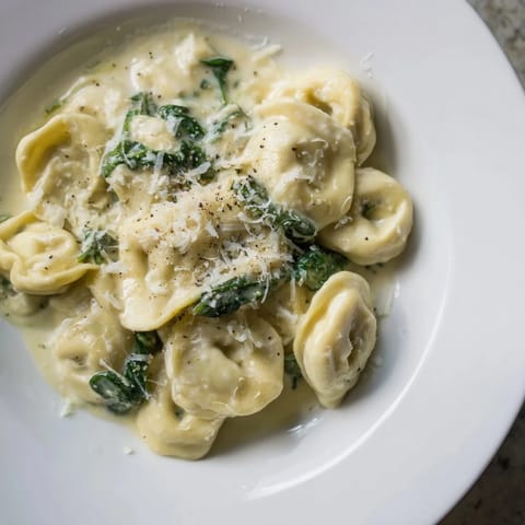 Enjoy a steaming bowl of Creamy Spinach Alfredo Tortellini, with tender pasta in a creamy sauce.