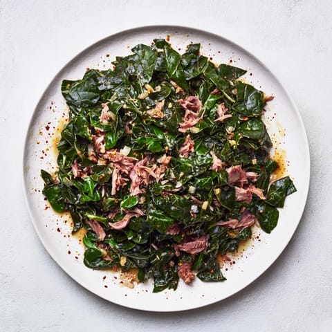 A close-up of steaming Southern collard greens with smoked turkey: showcasing the savory, slow-cooked goodness.