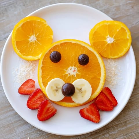 Vibrant Orange Slice Bear Face Fruit Board ready, featuring blueberries as tiny eyes and noses.