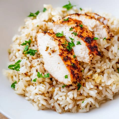 A close-up reveals steaming garlic butter rice and sliced grilled chicken breast, ideal for a quick weeknight dinner. 