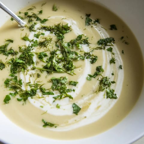 Creamy roasted parsnip and herb soup topped with fresh green herbs in a cozy ceramic bowl.  